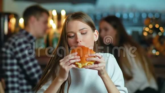 年轻快乐的女人在咖啡馆吃美味的快餐汉堡视频的预览图