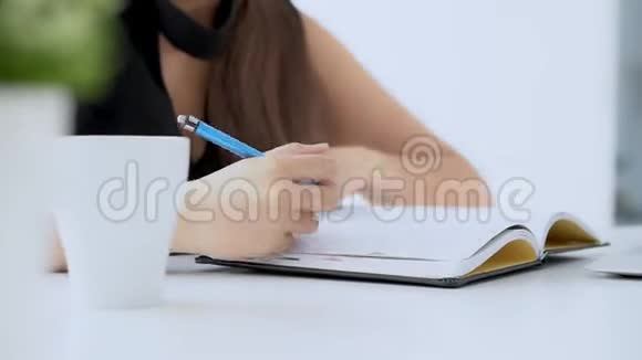 贴身女人坐在客厅里学习在家写笔记本和日记视频的预览图