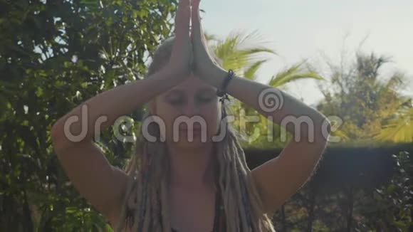 一位年轻女子在自家后院做纳玛斯卡式瑜伽视频的预览图