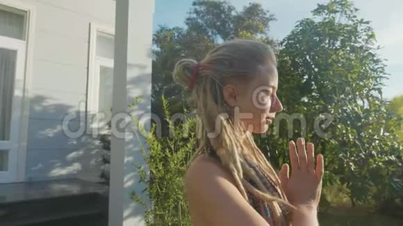 一位年轻女子在自家后院做纳玛斯卡式瑜伽视频的预览图