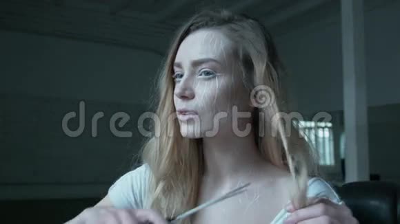 一个年轻的女人用大剪刀剪头发一个金发碧眼的金发女郎脸上有一个富有表现力的妆容使自己成为一个新的人视频的预览图