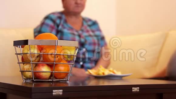 成年妇女坐在家里的桌子上吃新鲜水果视频的预览图