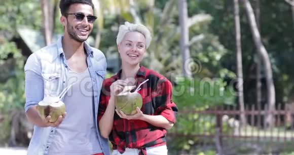 情侣饮料椰子鸡尾酒会在棕榈树上交谈快乐男人和女人微笑游客交流视频的预览图