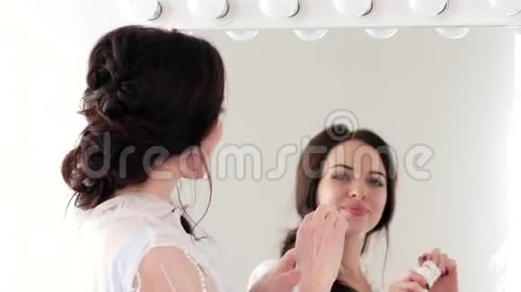 年轻女士柔软无瑕的皮肤在她的手和脸颊上涂抹奶油的女性特写视频的预览图