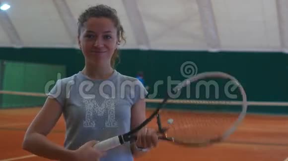 美丽的女孩拿着网球拍在球场上微笑视频的预览图