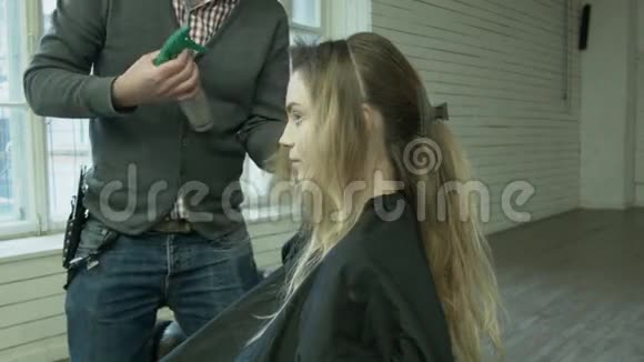 一个专业的理发师在那里为一个年轻的女人做发型一位男性造型师用视频的预览图