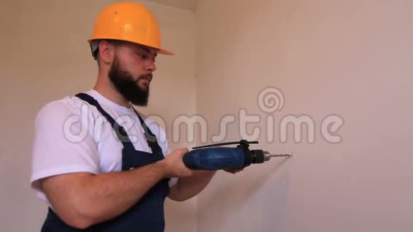 施工工人和杂工用蓝色电钻在施工现场的墙上钻一个钉子孔视频的预览图