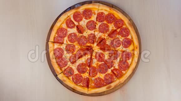 把意大利腊肠披萨切在桌子上的木板上特写俯视图视频的预览图