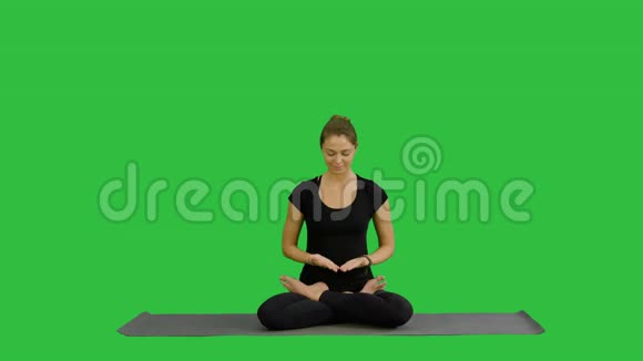 年轻女子在绿色屏幕上练习瑜伽时进行冥想Chroma键视频的预览图
