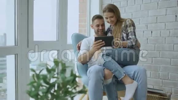 年轻快乐的夫妇在现代阁楼公寓的阳台上聊天和使用平板电脑视频的预览图