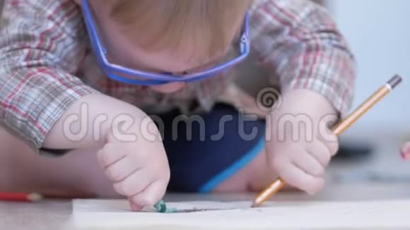 可爱的男孩戴着滑稽的眼镜两只手在家里用纸画画视频的预览图