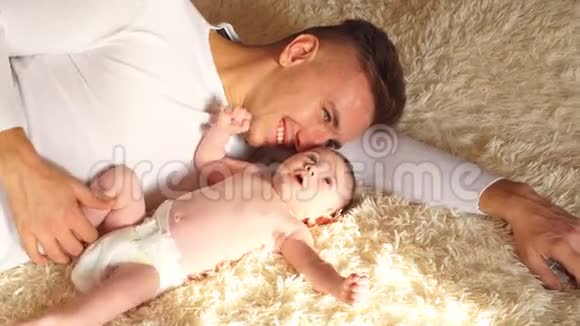 年轻的父亲和他的小儿子在床上拥抱视频的预览图