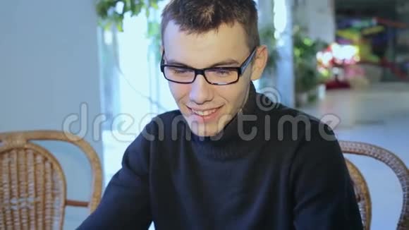 带眼镜的家伙在一家带平板电脑的咖啡馆里视频的预览图