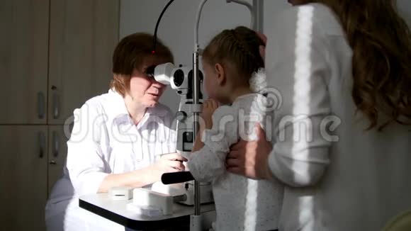 一个可爱的金发小女孩妈妈在儿童眼科验光师诊断视力视频的预览图