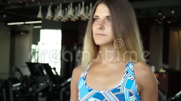 漂亮的女孩在健身房的跑步机上跑步全脸画像视频的预览图