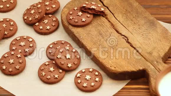 旧木工切割板上的粘土杯中的热牛奶和新鲜的烤巧克力饼干视频的预览图