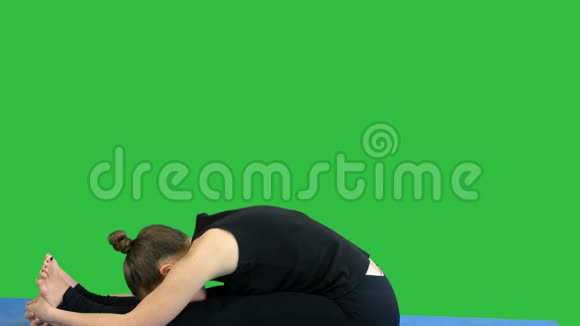 年轻女子在垫子上伸展腿在绿色屏幕上练习瑜伽Chroma键视频的预览图