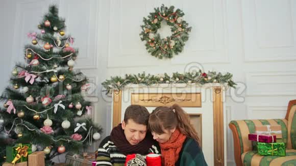 圣诞节和新年主题一对年轻夫妇互相喜欢拔罐热咖啡一间有圣诞树的房间视频的预览图