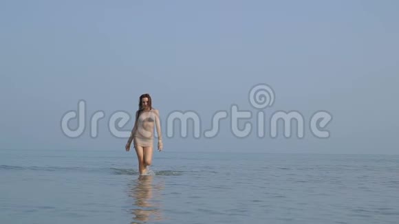 热辣的美女走在海里优雅吸引人的女孩正在腿上溅起水滴视频的预览图