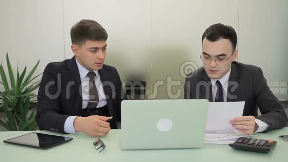 两个经理在现代办公室里坐在桌旁手提电脑视频的预览图