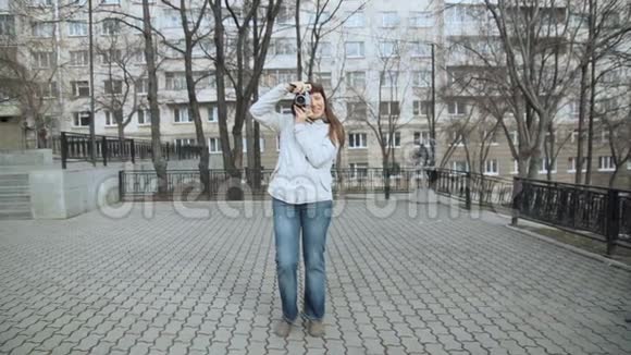 一位女士正在城市环境中拍摄老式复古风格的相机视频的预览图