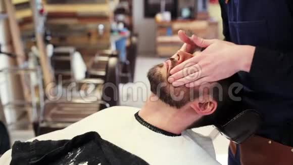 理发师在男性脸上涂胡子笔视频的预览图