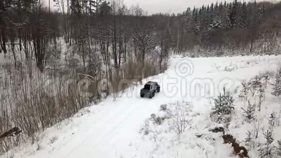 一辆6x6越野车的鸟瞰图它在冬天森林里的雪覆盖的道路上行驶视频的预览图