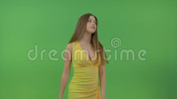 美丽的年轻女孩穿着黄色的裙子在绿色的屏幕上她转过身用手做了个手势视频的预览图