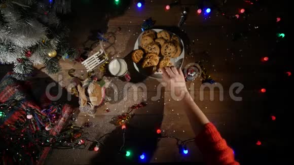 木制棕色桌子上面装饰着圣诞用品和花环男人手从盘子里拿饼干顶部视图视频的预览图
