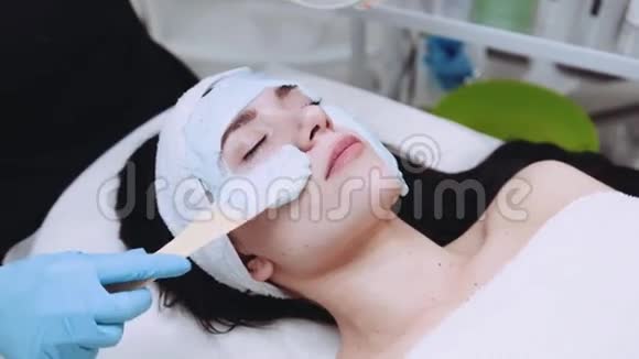 一个年轻的女性脸被一个专业的美容师用有机美颜面具覆盖着皮肤视频的预览图