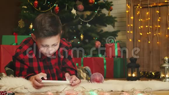 圣诞前夜男孩在玩他的数码平板电脑视频的预览图