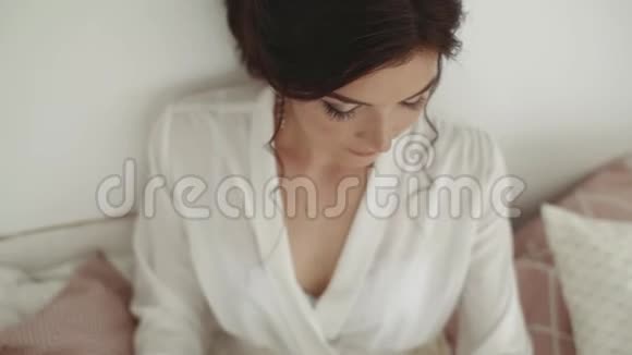 一个穿着晨衣的黑发女孩坐在床上新娘的照片视频的预览图