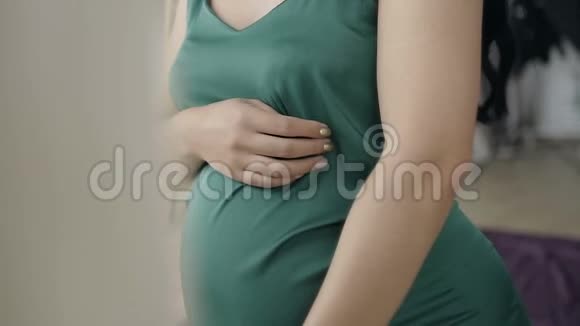 一位孕妇婴儿的肚子摇晃穿绿色衣服的孕妇视频的预览图