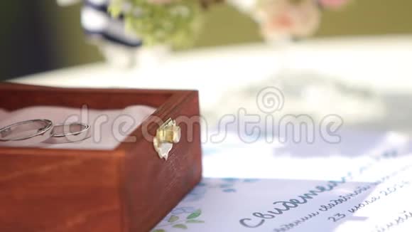 桌子上的木箱里放着白金结婚戒指的宏观镜头户外婚礼装饰视频的预览图