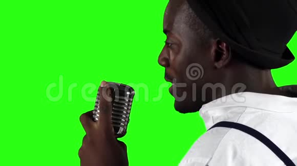 一个年轻的非洲裔美国人从后面的视线接近麦克风在录音室唱歌绿色屏幕视频的预览图