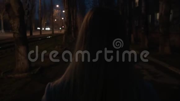 一个女人晚上沿着街走一个穿滑轮鞋的女孩要去见她我们从后面跟着金发女郎视频的预览图