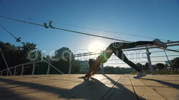 活跃的女性剪影锻炼和伸展在城市公园的人行天桥视频的预览图