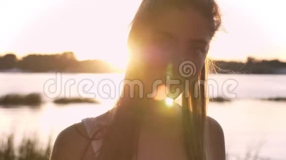 年轻美丽的女人在镜头中微笑的肖像镜头耀斑河流和自然背景视频的预览图