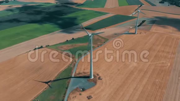 风轮机和风力发电机在夏季的一天在大片开阔天空的小麦作物上运行的鸟瞰图视频的预览图