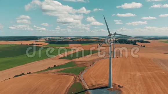 风轮机和风力发电机在夏季的一天在大片开阔天空的小麦作物上运行的鸟瞰图视频的预览图