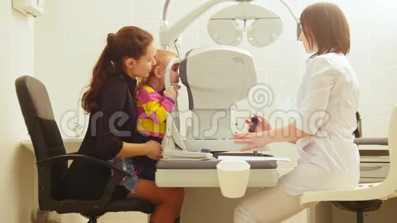 母亲和女儿在眼科医生的房间验光师在诊所检查小孩视力视频的预览图