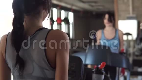 年轻女子在健身房里喝干净的水锻炼一个女孩在跑步机上行走视频的预览图