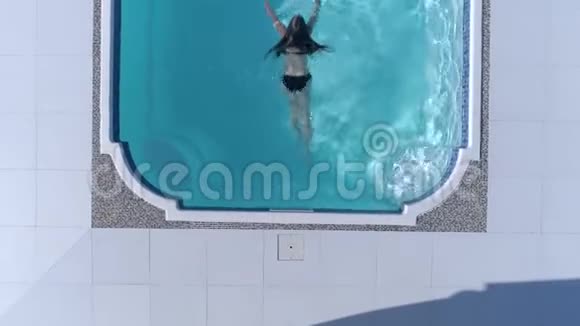 暑假时年轻女子的泳衣漂浮在蓝色的游泳池里视频的预览图