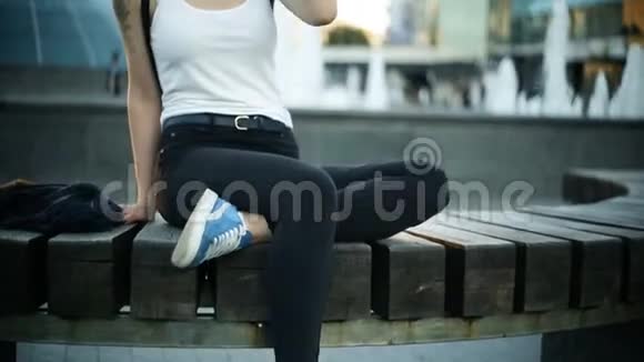 年轻的金发女人坐在长凳上等着往远处看直发相机泵视频的预览图