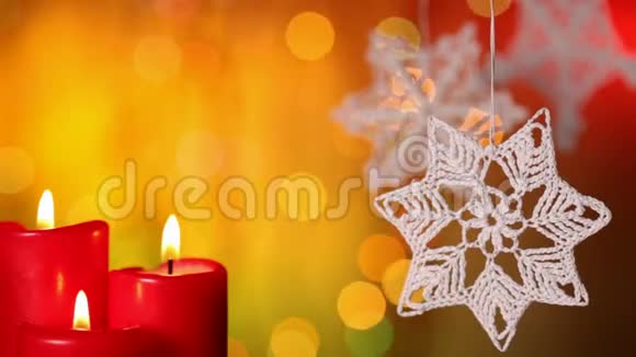 三支圣诞蜡烛和圣诞装饰品挂在模糊的灯光背景上视频的预览图