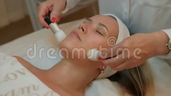 美容师两把刷子在女人的脸上做按摩眼睛紧闭视频的预览图
