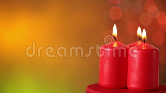 三支燃烧的圣诞蜡烛在暖色模糊的圣诞背景下旋转视频的预览图