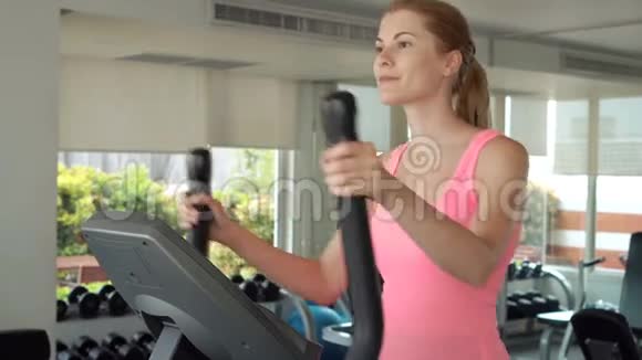 漂亮的健身运动积极的年轻女子在健身房锻炼椭圆健身教练视频的预览图