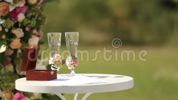 桌子上的木箱里装着白金结婚戒指用马和浆果装饰的眼镜财务报表视频的预览图