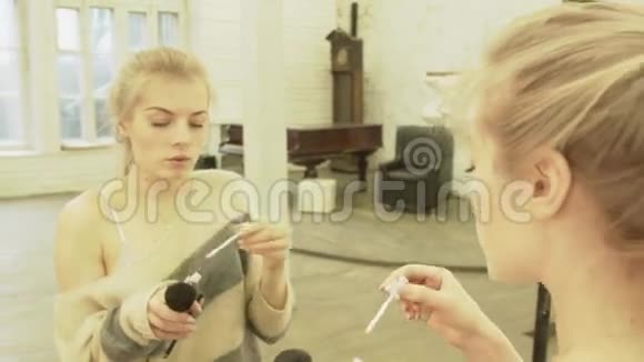 金发女郎对着镜子画嘴唇微笑一位美丽的年轻女子在大厅里用一个视频的预览图